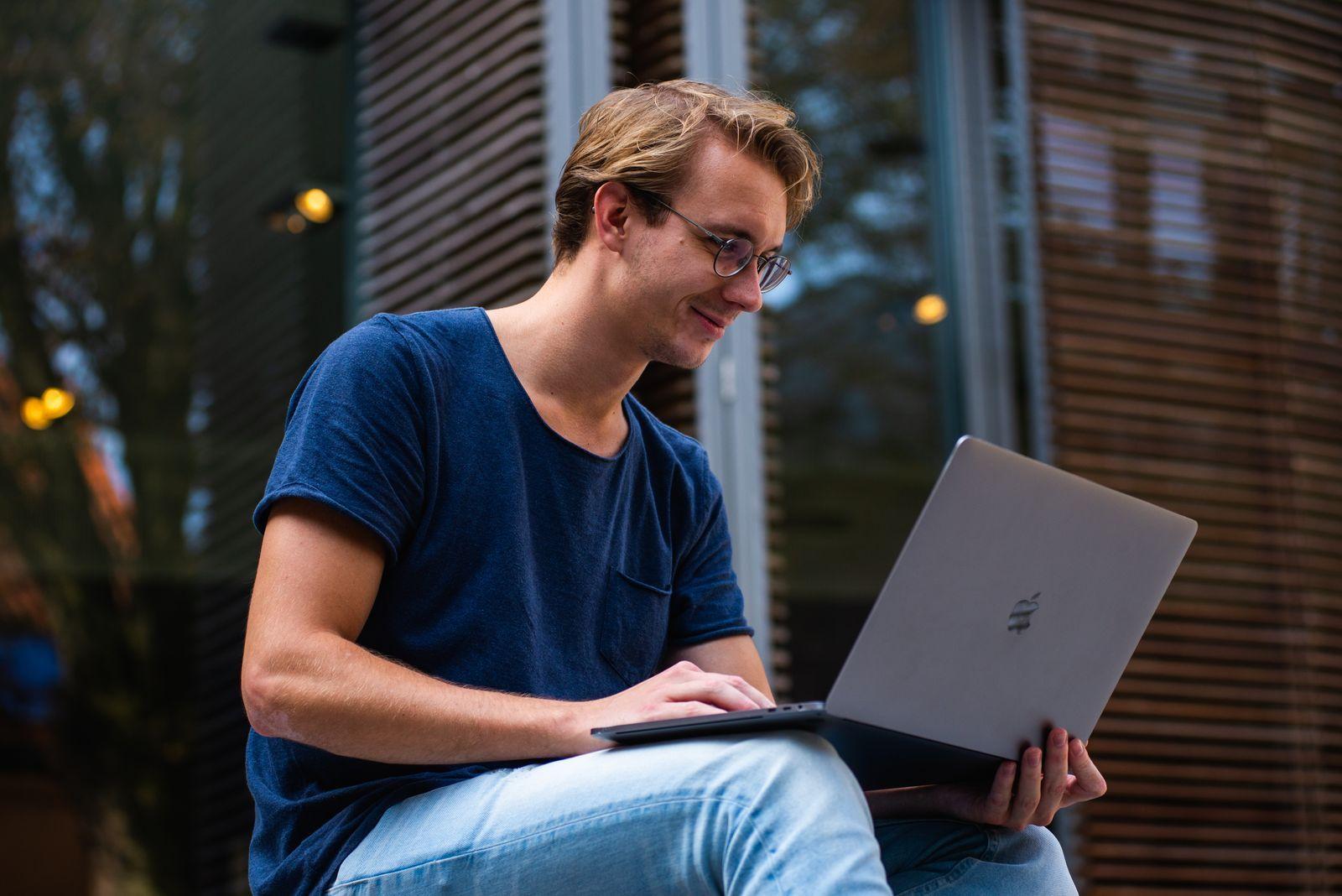 Smiling while using a laptop outdoors